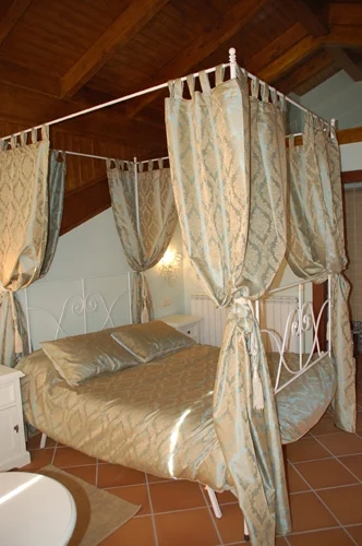 Cama con dosel y techo de madera en Casa Rojanda